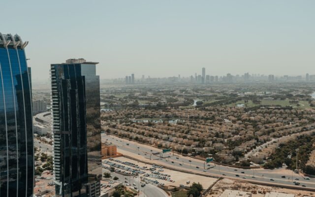A panoramic aerial view of Dubai's urban skyline featuring modern skyscrapers and residential areas.