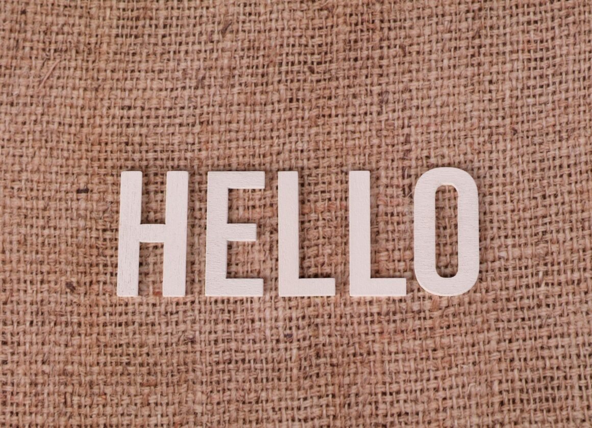 Wooden letters form the word 'HELLO' on a rustic burlap background, offering warm greetings.