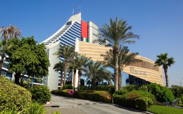 Explore the vibrant Jumeirah architecture with lush palm trees under a clear Dubai sky.