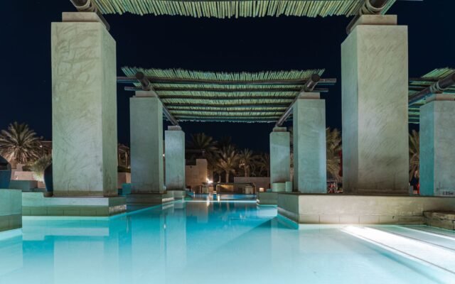 Stunning poolside view of a luxury hotel in Dubai by night, perfect for relaxation.